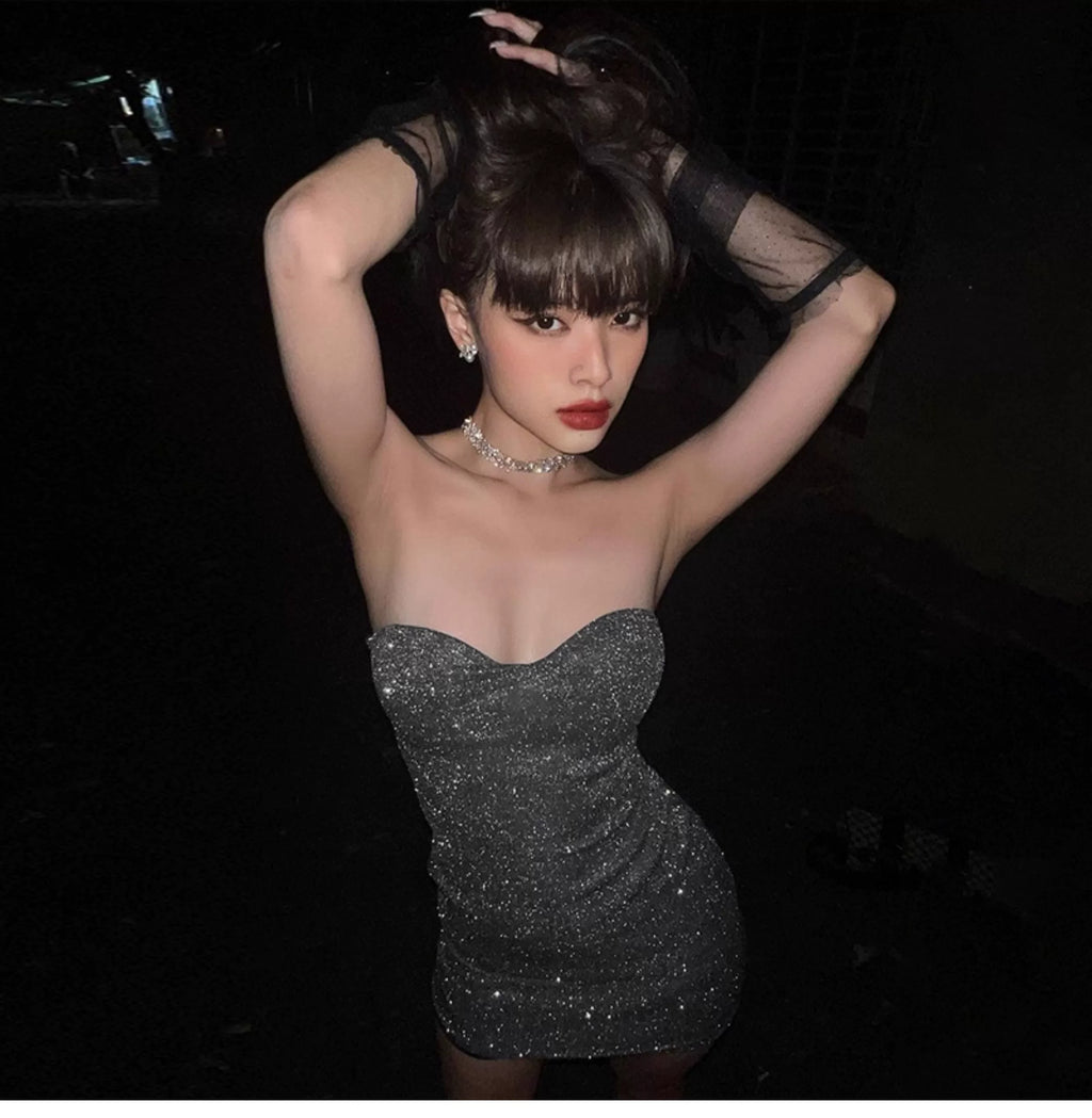A feminine one-shoulder shiny wrap-around bustier dress in solid color with pleated high waistline, creating an illusion of slimming and a curvy figure. Short skirt.